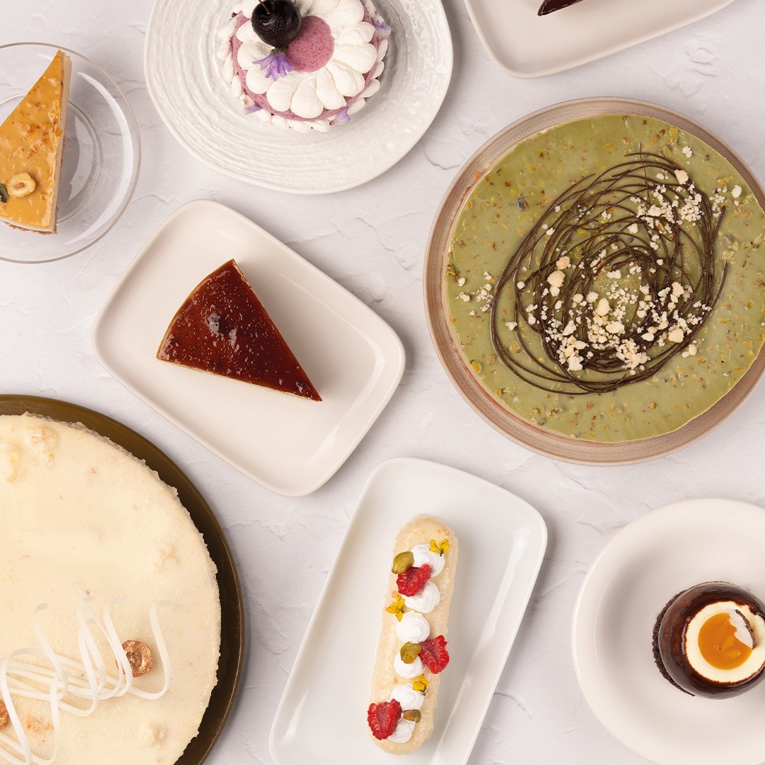 Felülnézeti kép desszertekről: sajttorta, flan, pisztáciás torta, eclair és csokoládémousse poharak