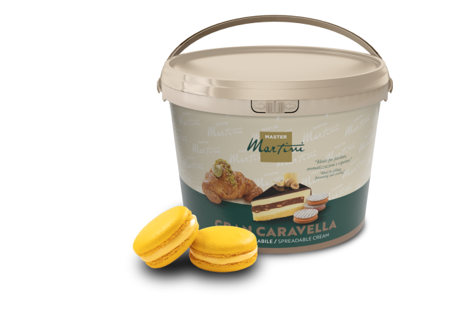 Bézs vödör Master Martini Gran Caravella kenhető krém két sárga macaron és egy töltött sütemény mellett.